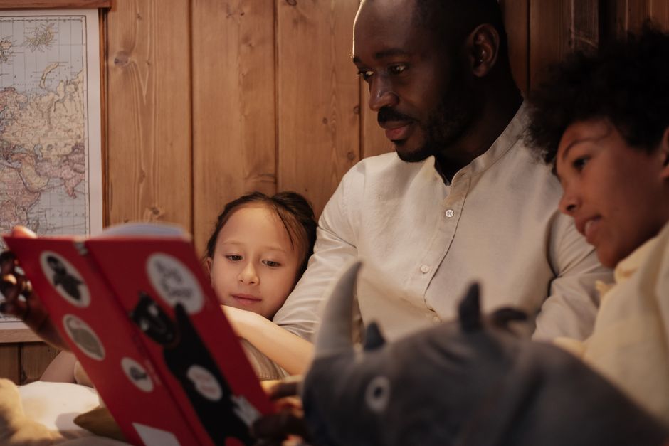 Father and children reading a storybook together in a cozy home setting, highlighting family bonding.